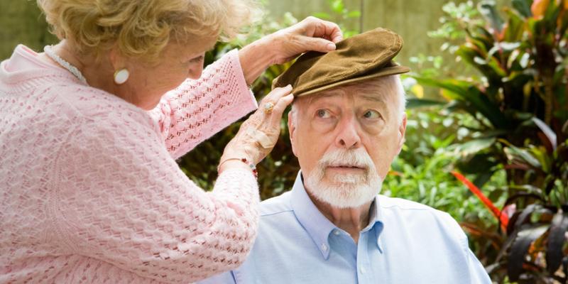 Elderly lady fixing elderly mans hat