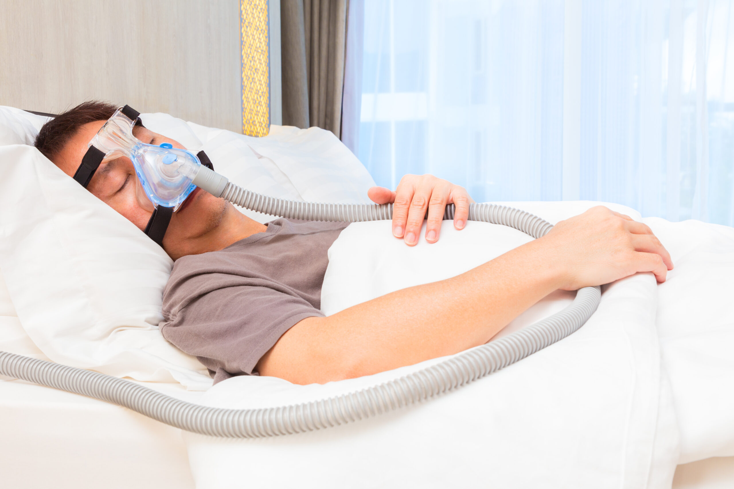 Man wearing CPAP machine in bed sleeping.