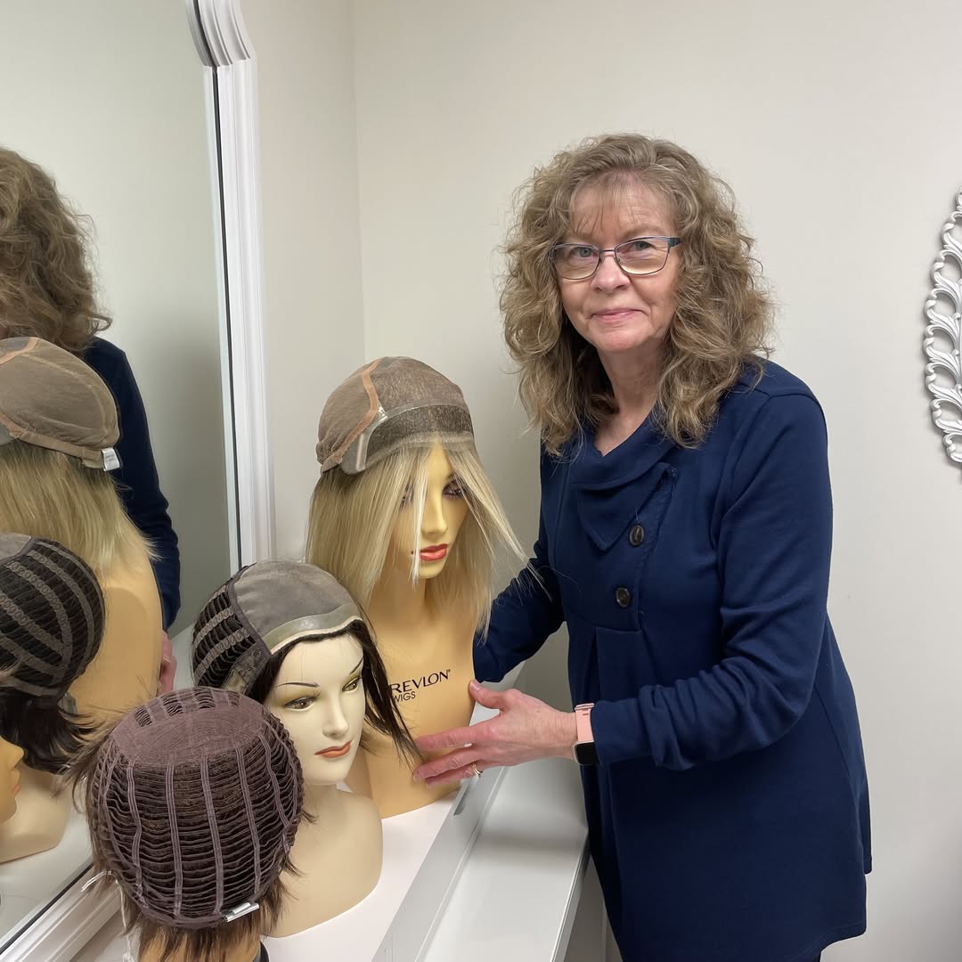 Donna Taylor standing by wigs.